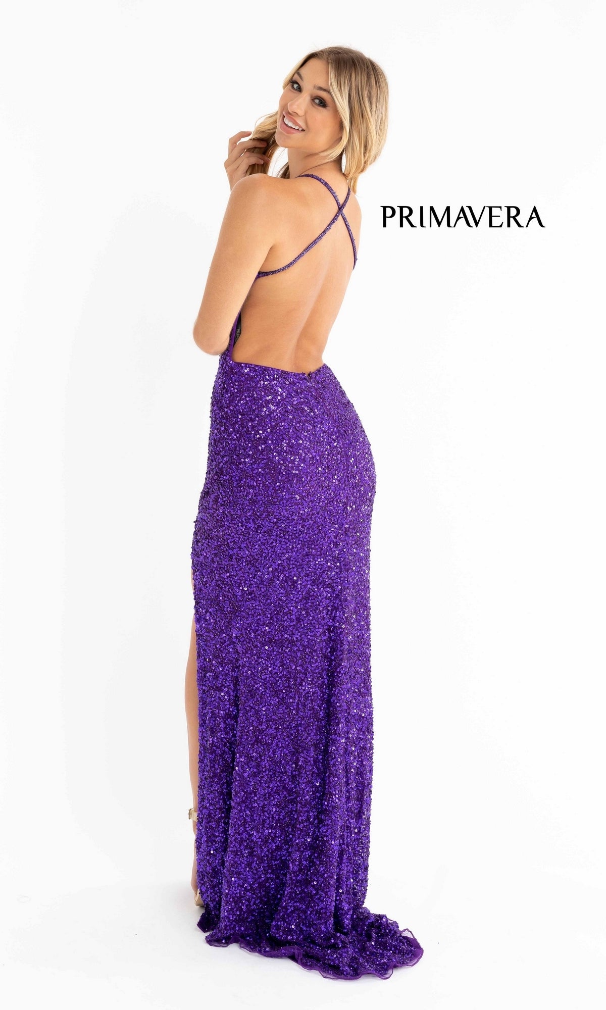 A woman in the Backless Tight Long Sequin Prom Dress 3291D—floor-length, purple, with crisscross straps—stands looking over her shoulder.
